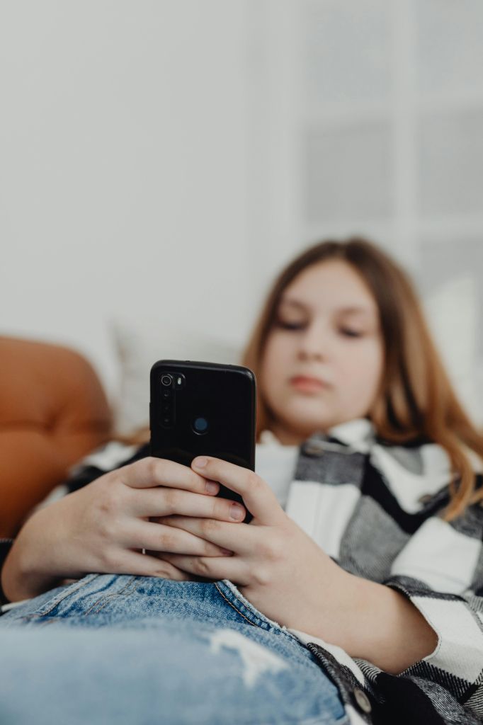 Jugendliche nutzt Smartphone auf dem Sofa